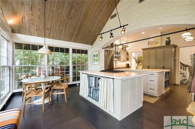 kitchen with a wealth of natural light, a kitchen island, hanging light fixtures, and high vaulted ceiling