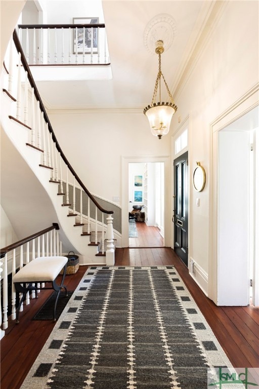 foyer featuring dark hardwood / wood-style flooring, a towering ceiling, and crown molding