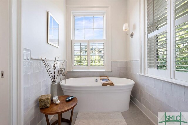 bathroom featuring tile walls, a wainscoted wall, and a freestanding bath