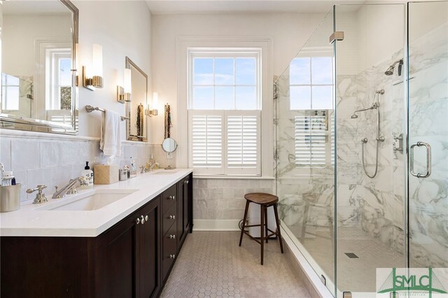 bathroom featuring tile patterned flooring, vanity, a shower with door, and tile walls