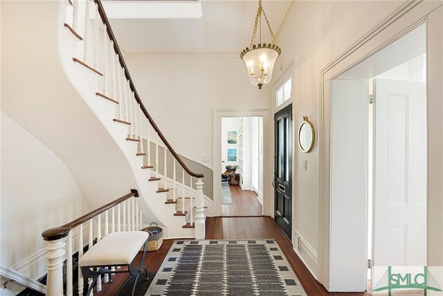 entryway featuring dark hardwood / wood-style flooring, an inviting chandelier, and crown molding