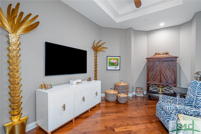 living room with wood-type flooring and a tray ceiling