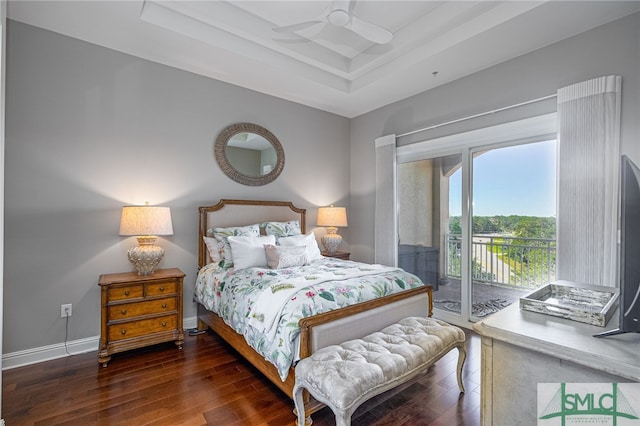 bedroom featuring dark hardwood / wood-style flooring, access to outside, ceiling fan, and a tray ceiling