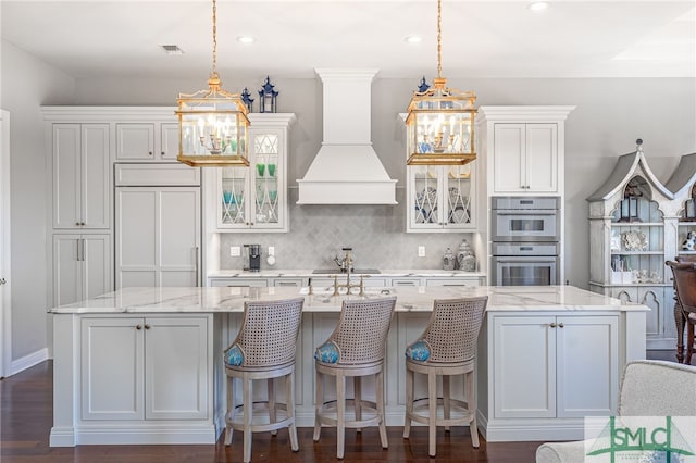 kitchen with a spacious island, custom range hood, paneled refrigerator, and double oven