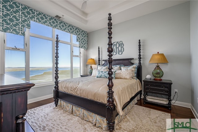 bedroom featuring a water view and hardwood / wood-style flooring