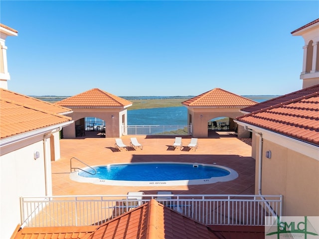 view of pool featuring a patio area and a water view