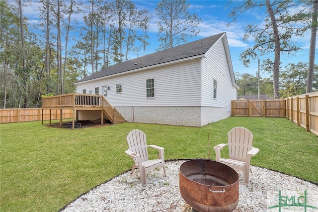 back of house featuring a lawn, a deck, and an outdoor fire pit