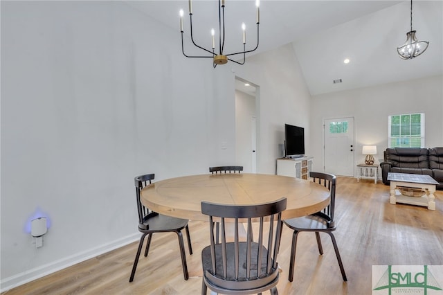 dining space featuring high vaulted ceiling, light hardwood / wood-style floors, and an inviting chandelier