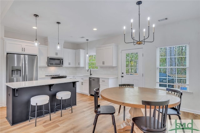 dining area with light wood-type flooring, sink, and an inviting chandelier