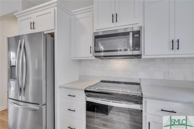 kitchen with backsplash, white cabinets, light hardwood / wood-style flooring, appliances with stainless steel finishes, and light stone counters