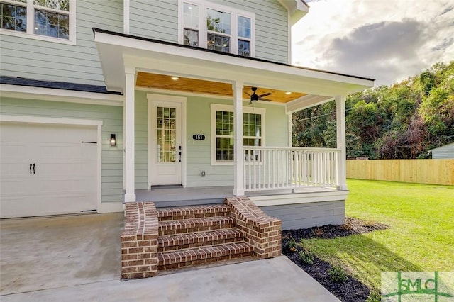 entrance to property featuring a yard, ceiling fan, a porch, and a garage