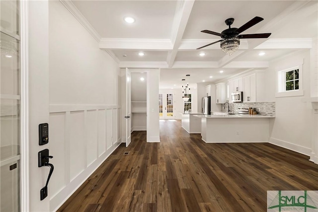 interior space with beam ceiling, dark hardwood / wood-style flooring, kitchen peninsula, and white cabinets