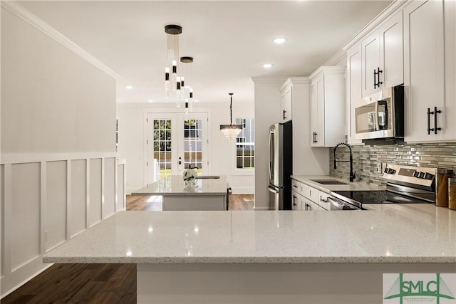 kitchen with appliances with stainless steel finishes, sink, light stone counters, decorative light fixtures, and white cabinets