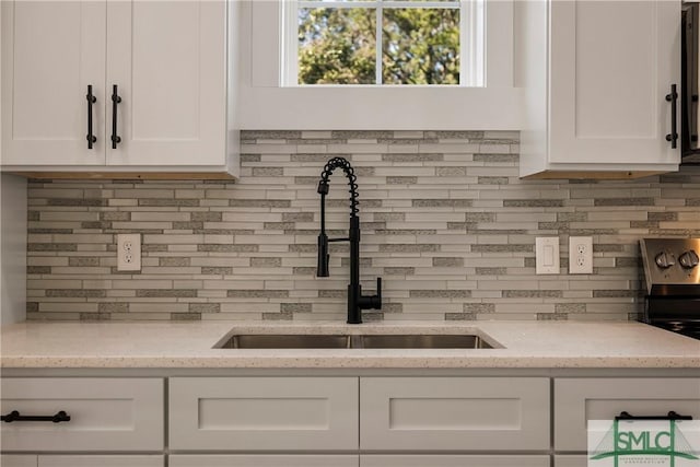 room details with sink, white cabinets, and light stone countertops