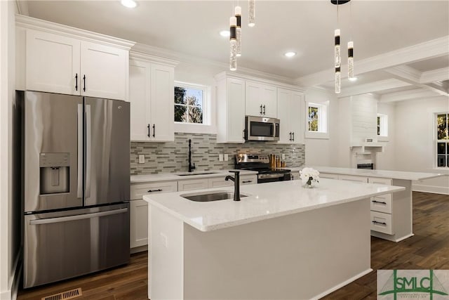 kitchen with a center island with sink, hanging light fixtures, stainless steel appliances, light stone counters, and white cabinetry