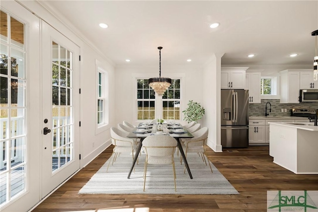 dining space with dark hardwood / wood-style flooring, sink, a chandelier, and crown molding