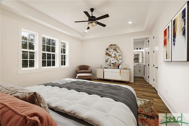 bedroom with dark hardwood / wood-style flooring, ceiling fan, a raised ceiling, and connected bathroom