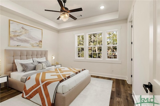 bedroom featuring dark hardwood / wood-style floors, ceiling fan, and a raised ceiling