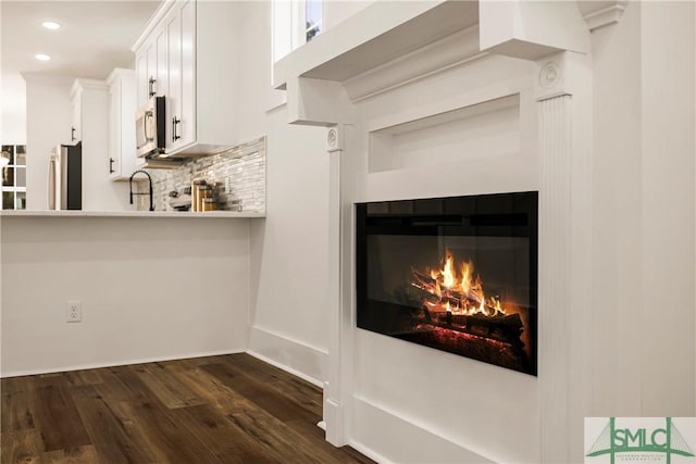 interior details featuring sink, backsplash, dark hardwood / wood-style floors, stainless steel appliances, and white cabinets