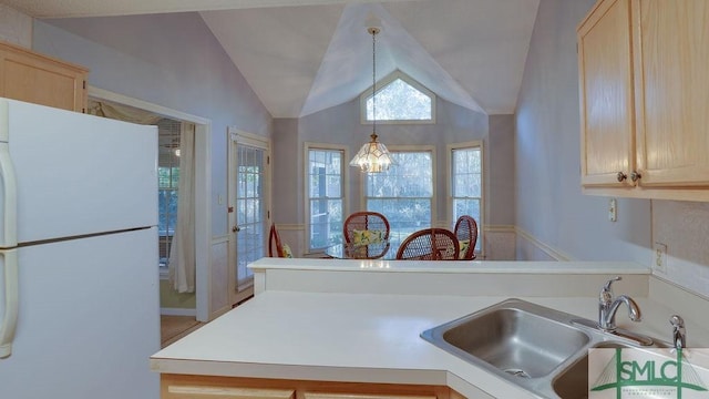 kitchen featuring light brown cabinets, sink, a notable chandelier, white refrigerator, and lofted ceiling