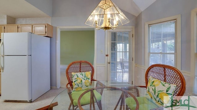 carpeted dining space with a chandelier and vaulted ceiling