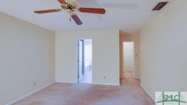 empty room featuring a textured ceiling, light colored carpet, and ceiling fan