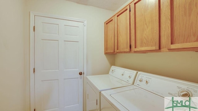 washroom with washing machine and dryer, cabinets, and a textured ceiling