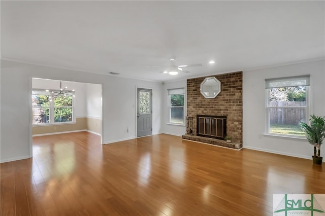 unfurnished living room featuring light hardwood / wood-style floors, a brick fireplace, plenty of natural light, and ornamental molding