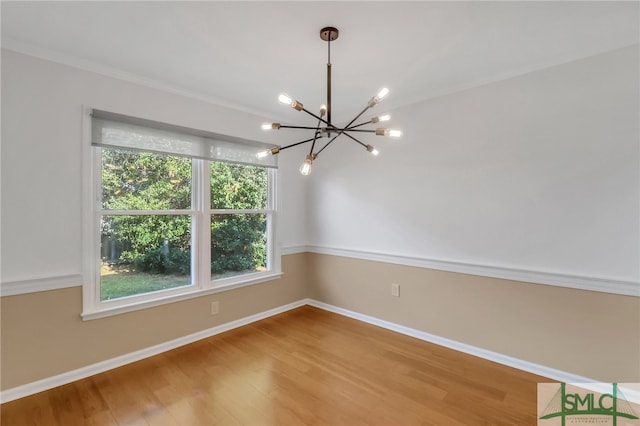 spare room with a notable chandelier and wood-type flooring