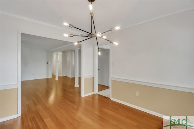 unfurnished room featuring ornamental molding, a notable chandelier, and hardwood / wood-style flooring