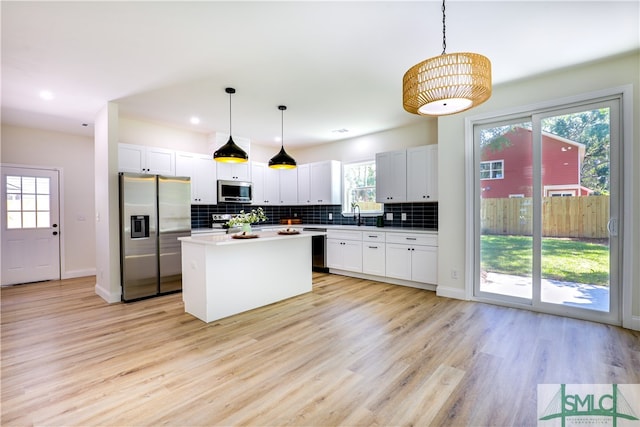 kitchen with a wealth of natural light, a kitchen island, pendant lighting, and appliances with stainless steel finishes