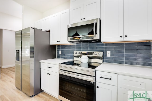 kitchen featuring appliances with stainless steel finishes, white cabinetry, light hardwood / wood-style flooring, and tasteful backsplash