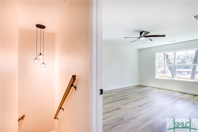 stairs with hardwood / wood-style floors and ceiling fan