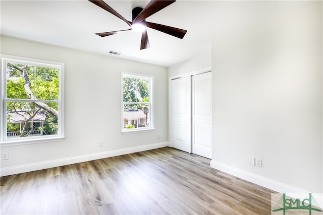 unfurnished bedroom featuring light hardwood / wood-style floors, multiple windows, and ceiling fan