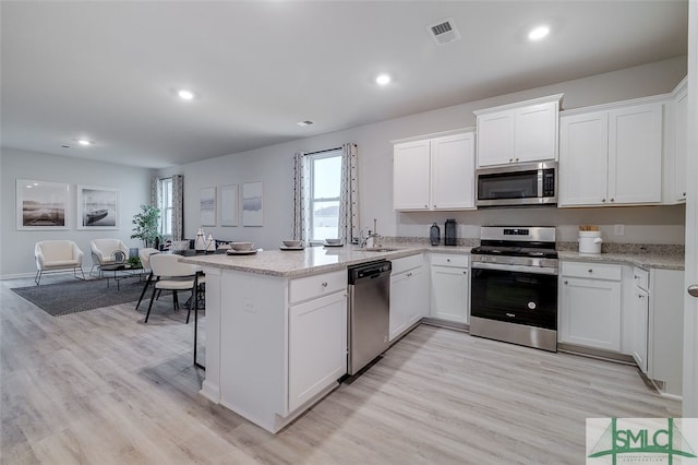 kitchen featuring sink, white cabinets, stainless steel appliances, and light hardwood / wood-style floors