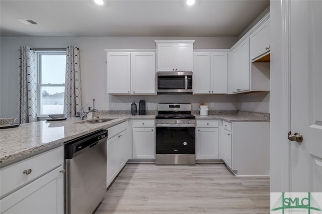 kitchen with sink, white cabinets, light hardwood / wood-style flooring, and appliances with stainless steel finishes