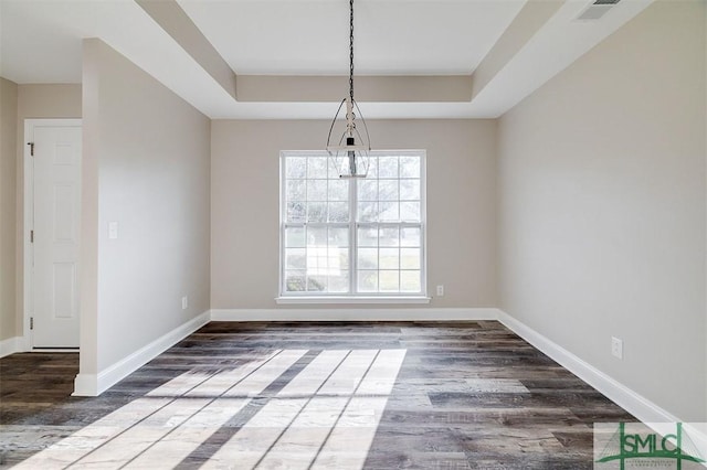 unfurnished dining area with a raised ceiling and dark hardwood / wood-style flooring