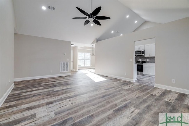 unfurnished living room with hardwood / wood-style flooring, ceiling fan with notable chandelier, and high vaulted ceiling