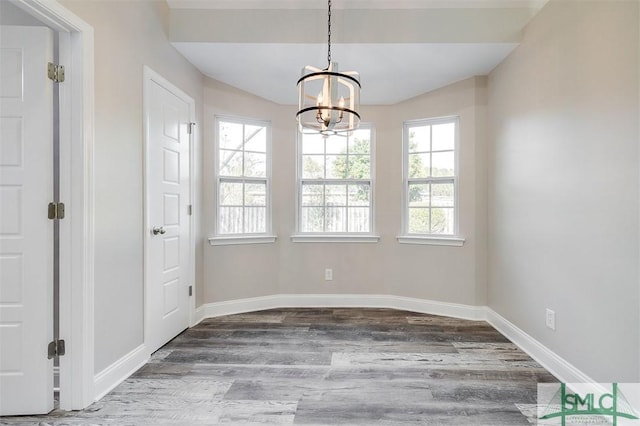 unfurnished dining area featuring a chandelier and wood-type flooring