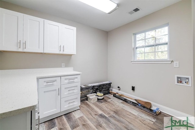 clothes washing area featuring light hardwood / wood-style floors, cabinets, and hookup for a washing machine