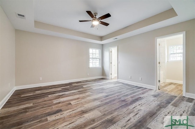 unfurnished room with a tray ceiling, ceiling fan, and wood-type flooring