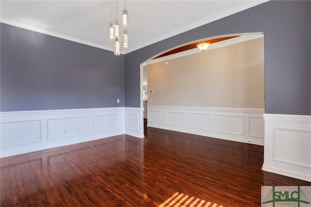 empty room with dark hardwood / wood-style flooring, ornamental molding, and a chandelier