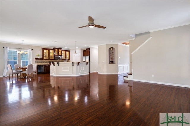 living room with ceiling fan with notable chandelier, dark hardwood / wood-style floors, and ornamental molding