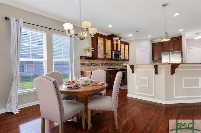 dining space featuring ornamental molding, dark wood-type flooring, and a notable chandelier