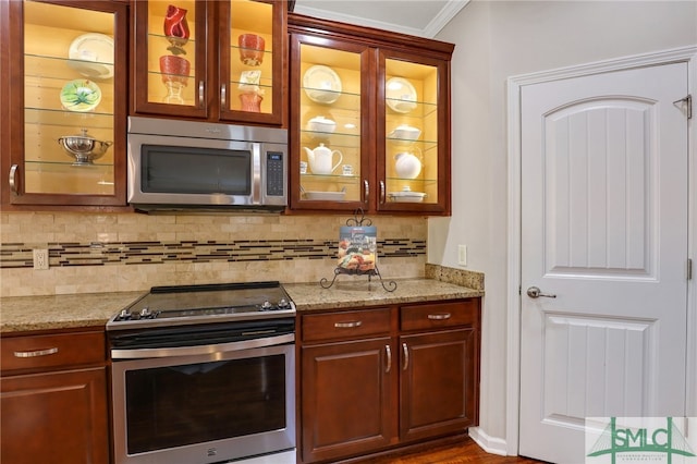 kitchen with light stone countertops, appliances with stainless steel finishes, backsplash, and crown molding