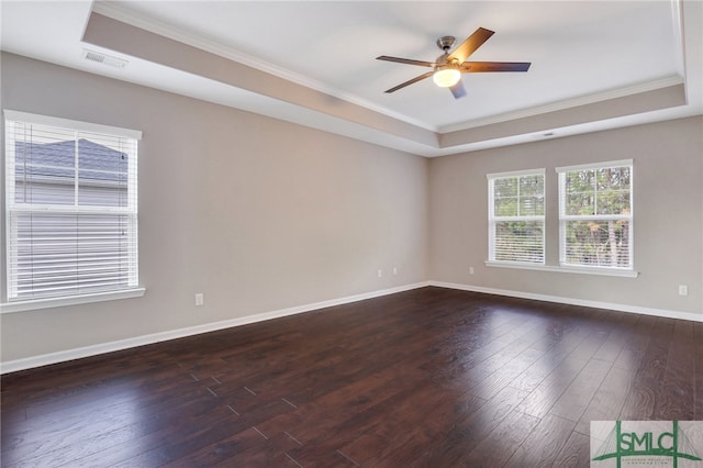 empty room with ceiling fan, crown molding, dark wood-type flooring, and a tray ceiling