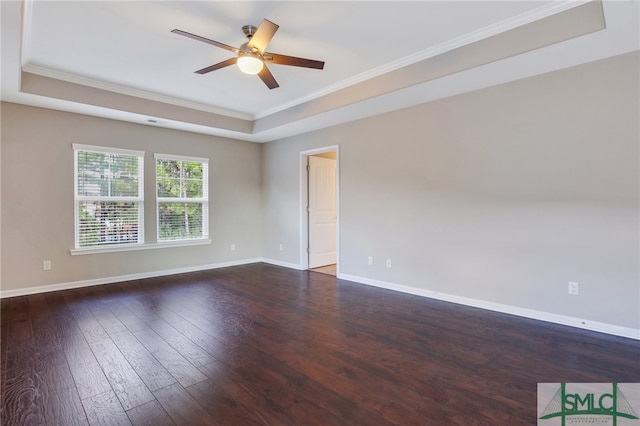 empty room with dark hardwood / wood-style floors, ceiling fan, crown molding, and a tray ceiling