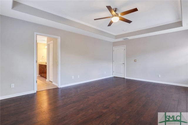 spare room with a tray ceiling, ceiling fan, crown molding, and dark hardwood / wood-style floors