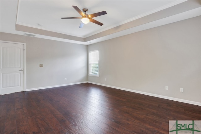 spare room with ornamental molding, a tray ceiling, ceiling fan, and dark wood-type flooring