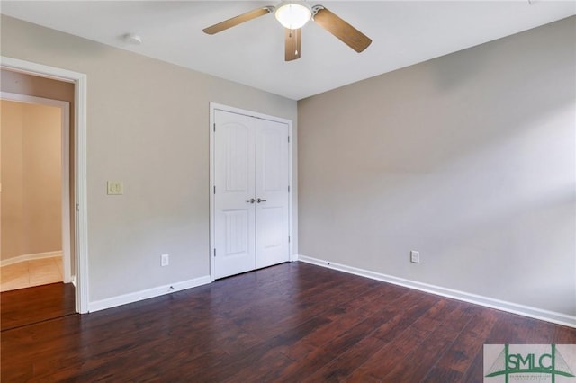 unfurnished bedroom with ceiling fan, dark wood-type flooring, and a closet